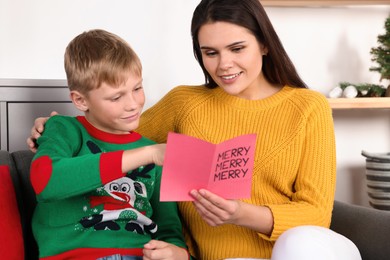 Happy woman receiving greeting card from her son at home