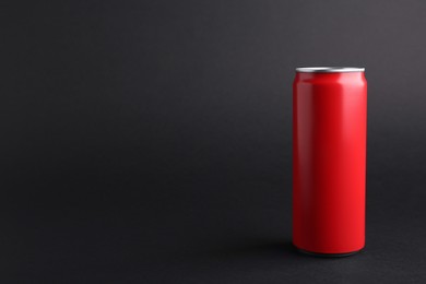 Photo of Energy drink in red can on black background, space for text