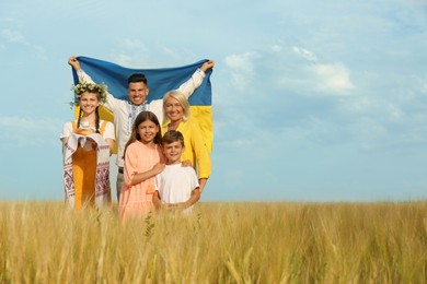 Photo of Happy family with national flag of Ukraine and treat in field. Space for text