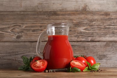 Photo of Tasty tomato juice in glass jug, fresh vegetables and spices on wooden table