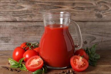 Tasty tomato juice in glass jug, fresh vegetables and spices on wooden table