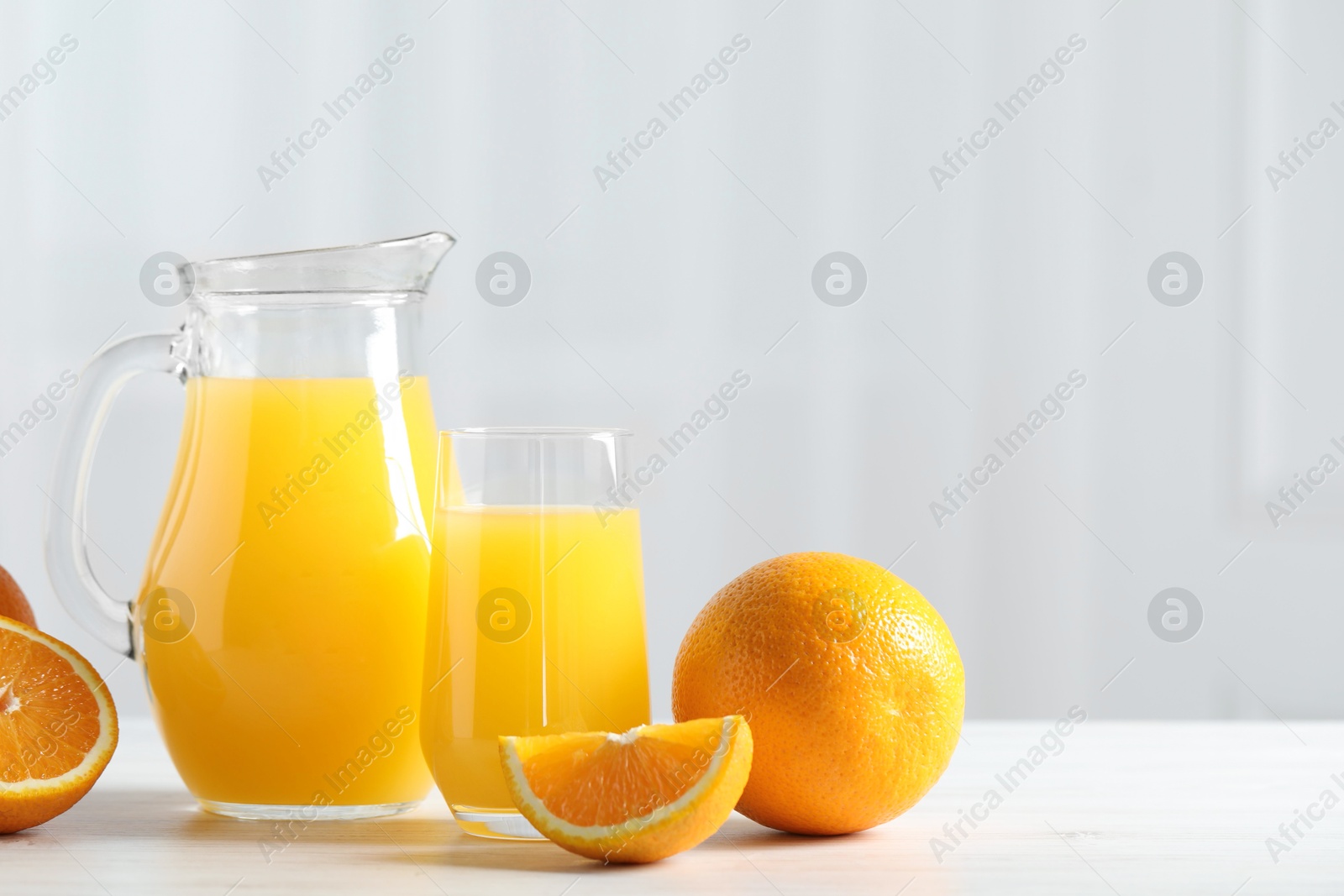 Photo of Tasty orange juice and fresh fruits on white wooden table. Space for text