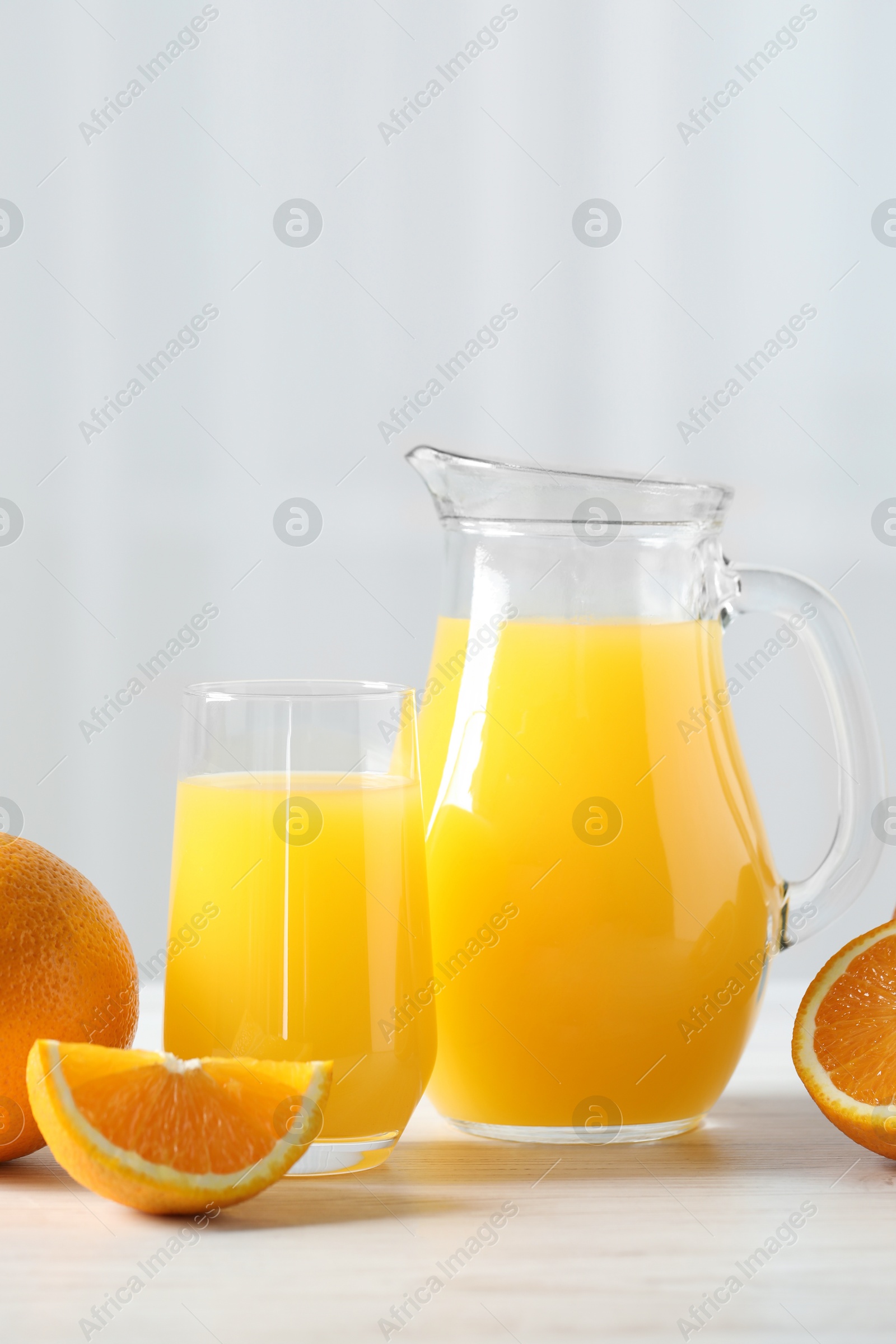 Photo of Tasty orange juice and fresh fruits on white wooden table