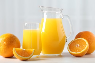 Photo of Tasty orange juice and fresh fruits on white wooden table