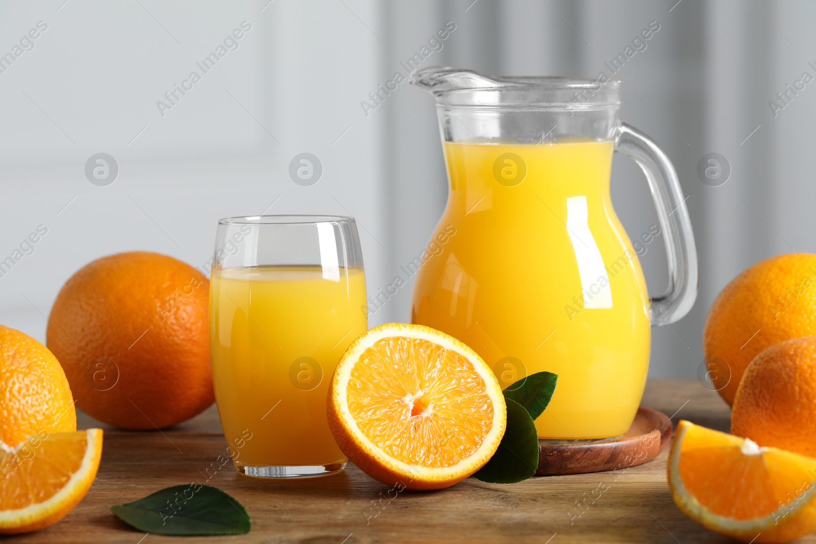 Photo of Tasty orange juice, green leaves and fresh fruits on wooden table