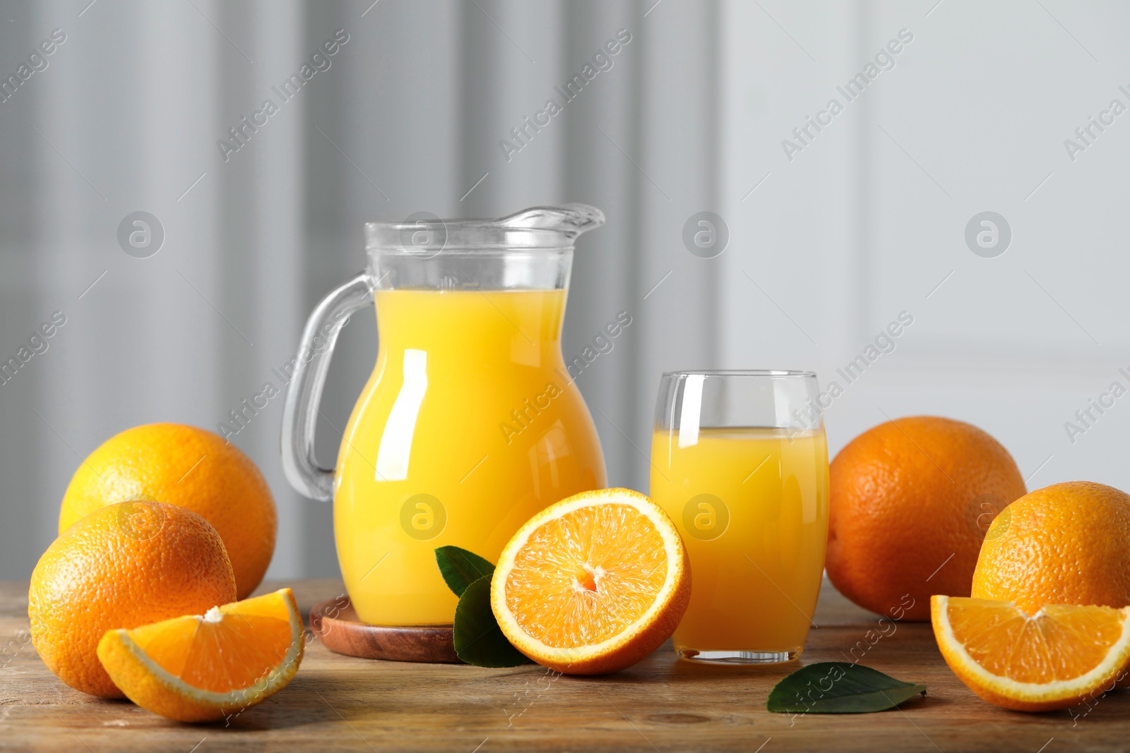 Photo of Tasty orange juice, green leaves and fresh fruits on wooden table