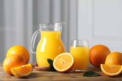 Photo of Tasty orange juice, green leaves and fresh fruits on wooden table