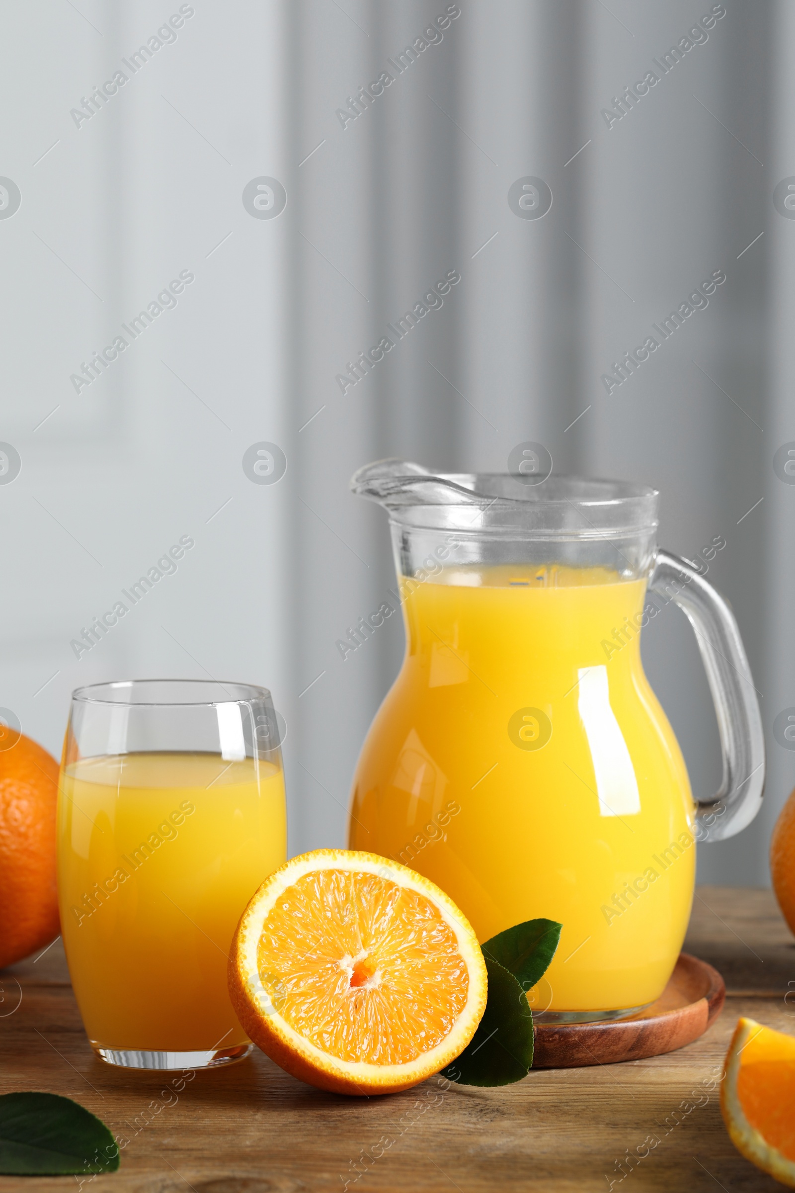 Photo of Tasty orange juice, green leaves and fresh fruits on wooden table