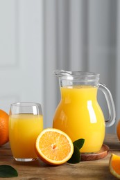 Tasty orange juice, green leaves and fresh fruits on wooden table