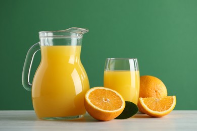 Photo of Tasty orange juice, fresh fruits and green leaf on white wooden table