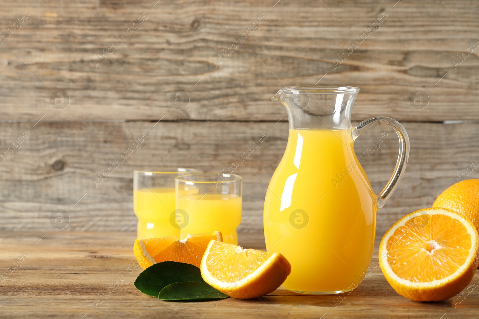 Photo of Tasty orange juice, fresh fruits and green leaf on wooden table