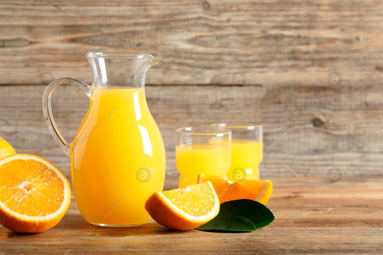 Photo of Tasty orange juice, fresh fruits and green leaf on wooden table. Space for text