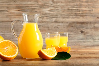 Photo of Tasty orange juice, fresh fruits and green leaf on wooden table. Space for text