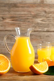 Photo of Tasty orange juice and fresh fruits on wooden table