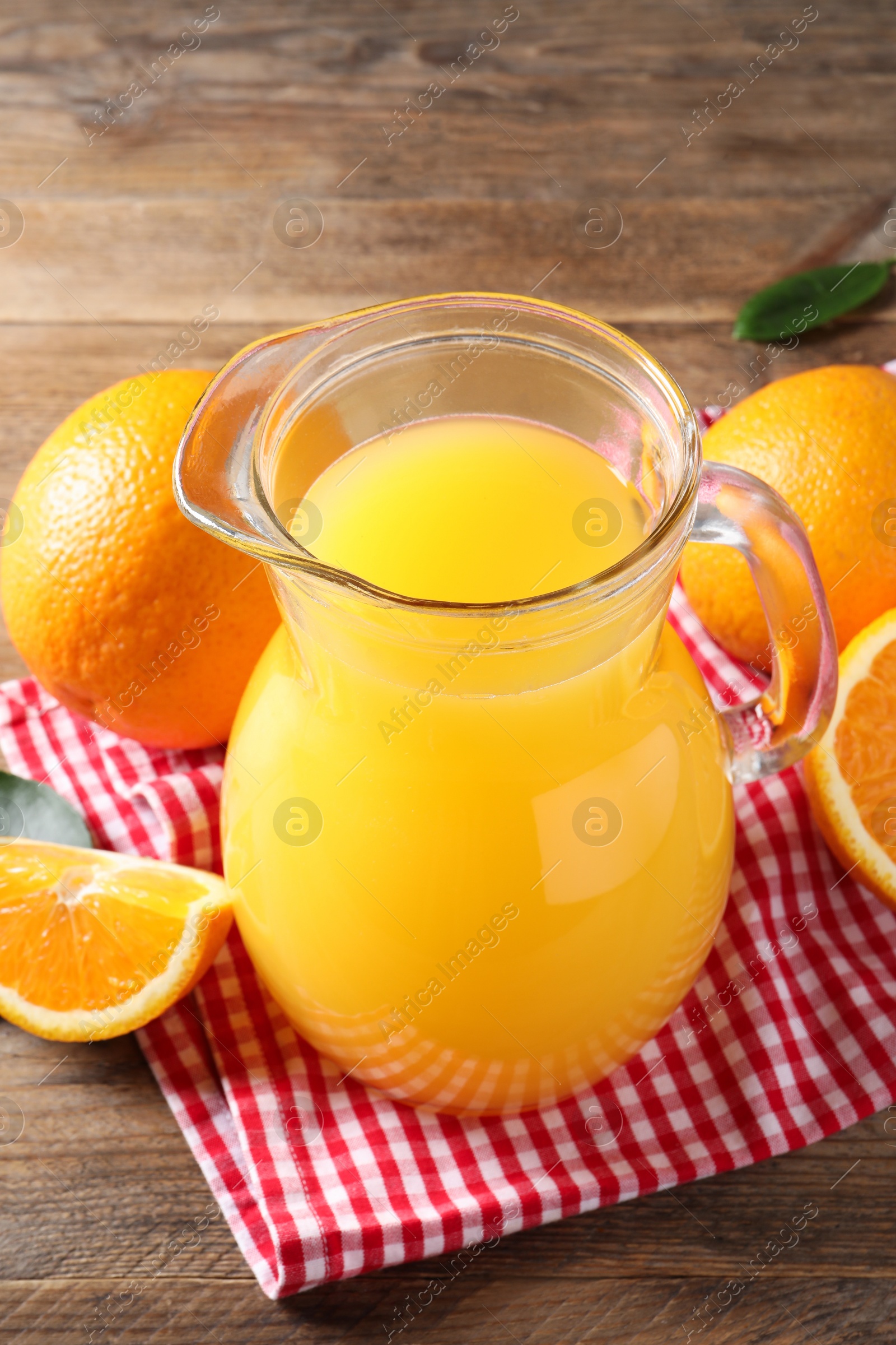 Photo of Tasty orange juice in glass jug and fresh fruits on wooden table