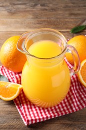 Tasty orange juice in glass jug and fresh fruits on wooden table