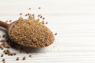 Coriander powder in spoon and seeds on wooden table, closeup. Space for text