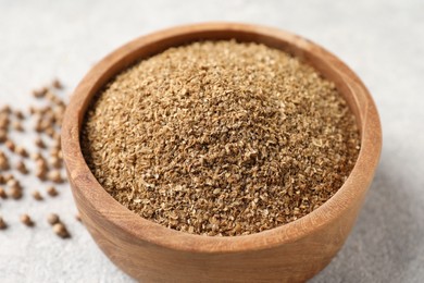 Photo of Coriander powder in bowl and seeds on light grey table, closeup