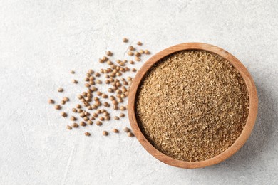 Photo of Coriander powder in bowl and seeds on light grey table, top view. Space for text