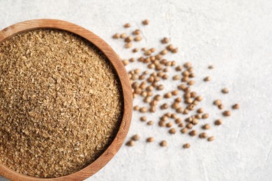 Photo of Coriander powder in bowl and seeds on light grey table, top view. Space for text