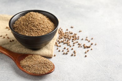 Photo of Coriander powder in spoon, seeds and green leaves on light grey table. Space for text