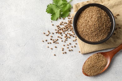 Photo of Coriander powder in bowl, spoon, seeds and green leaves on light grey table, top view. Space for text