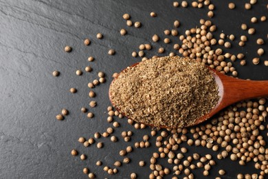 Photo of Coriander powder in spoon and seeds on black table, top view. Space for text