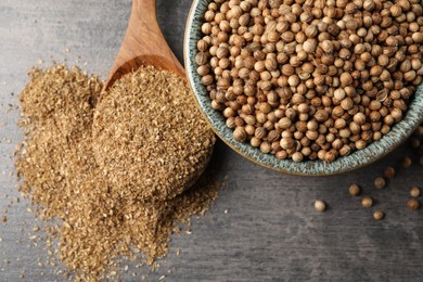 Photo of Dried coriander seeds in bowl and powder on grey table, top view