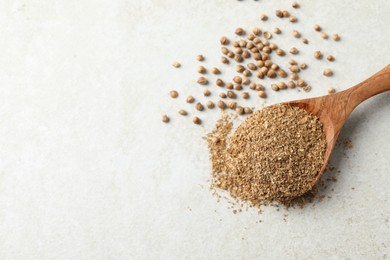 Coriander powder in spoon and seeds on light grey table, above view. Space for text