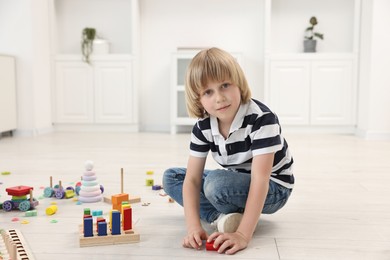 Photo of Cute little boy playing on floor indoors