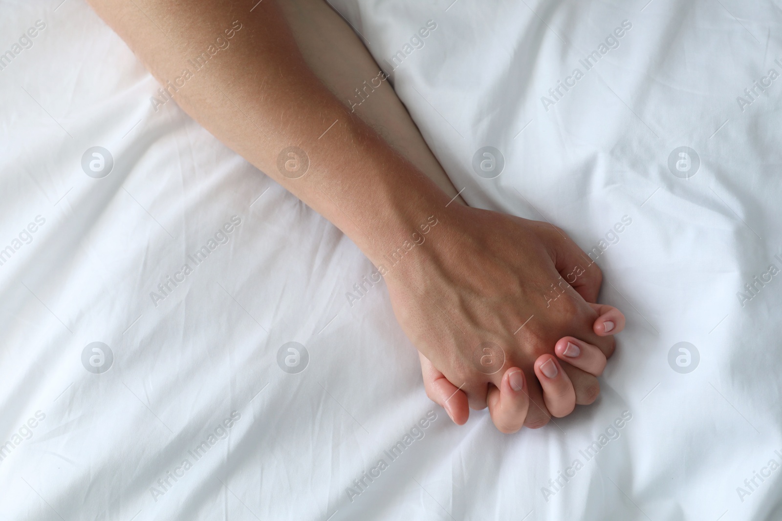 Photo of Lovely couple holding hands in bed, top view