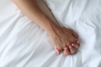 Photo of Lovely couple holding hands in bed, top view