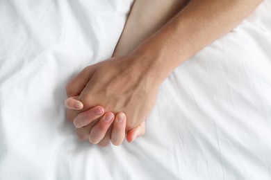 Photo of Lovely couple holding hands in bed, top view