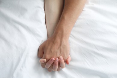 Lovely couple holding hands in bed, top view