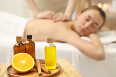 Photo of Aromatherapy. Woman receiving back massage in spa salon, focus on bottles of essential oils