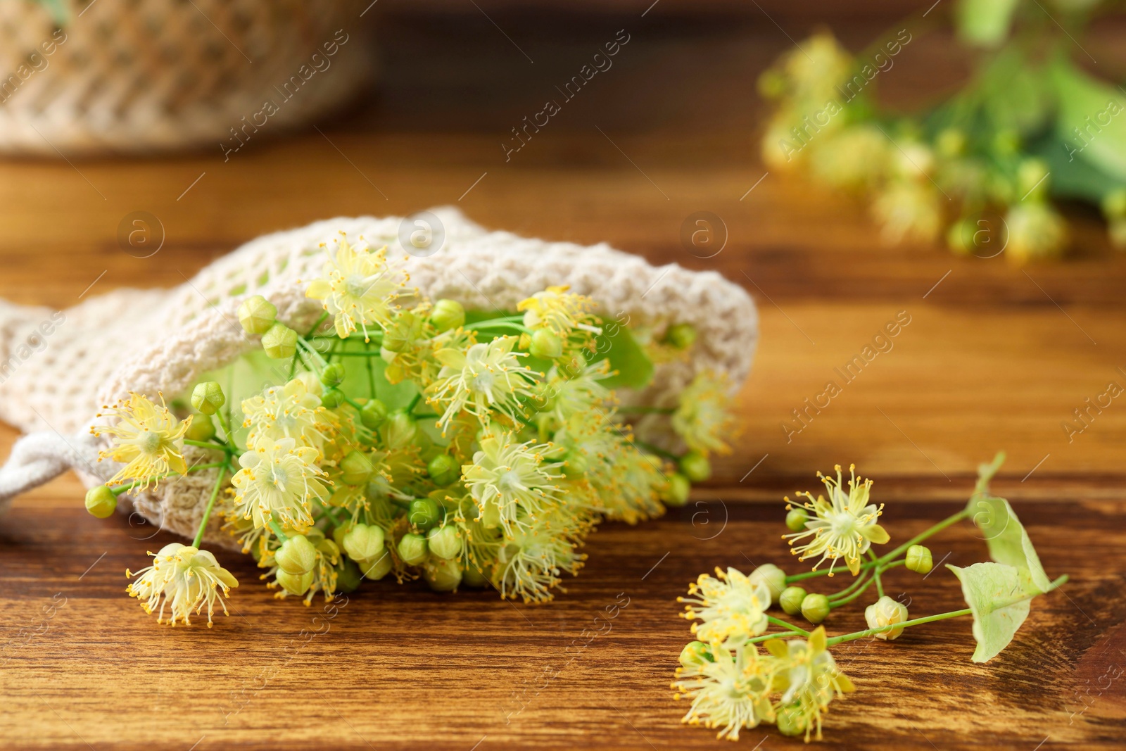 Photo of Fresh linden leaves and flowers on wooden table, closeup