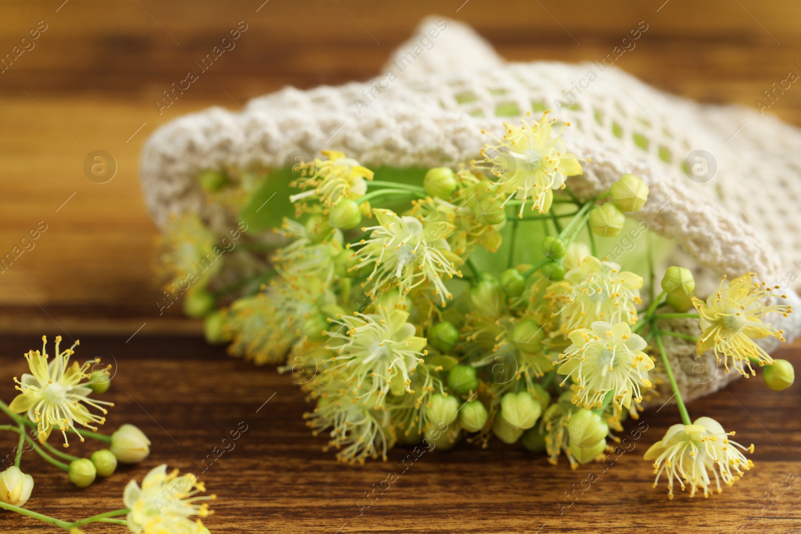 Photo of Fresh linden leaves and flowers on wooden table, closeup