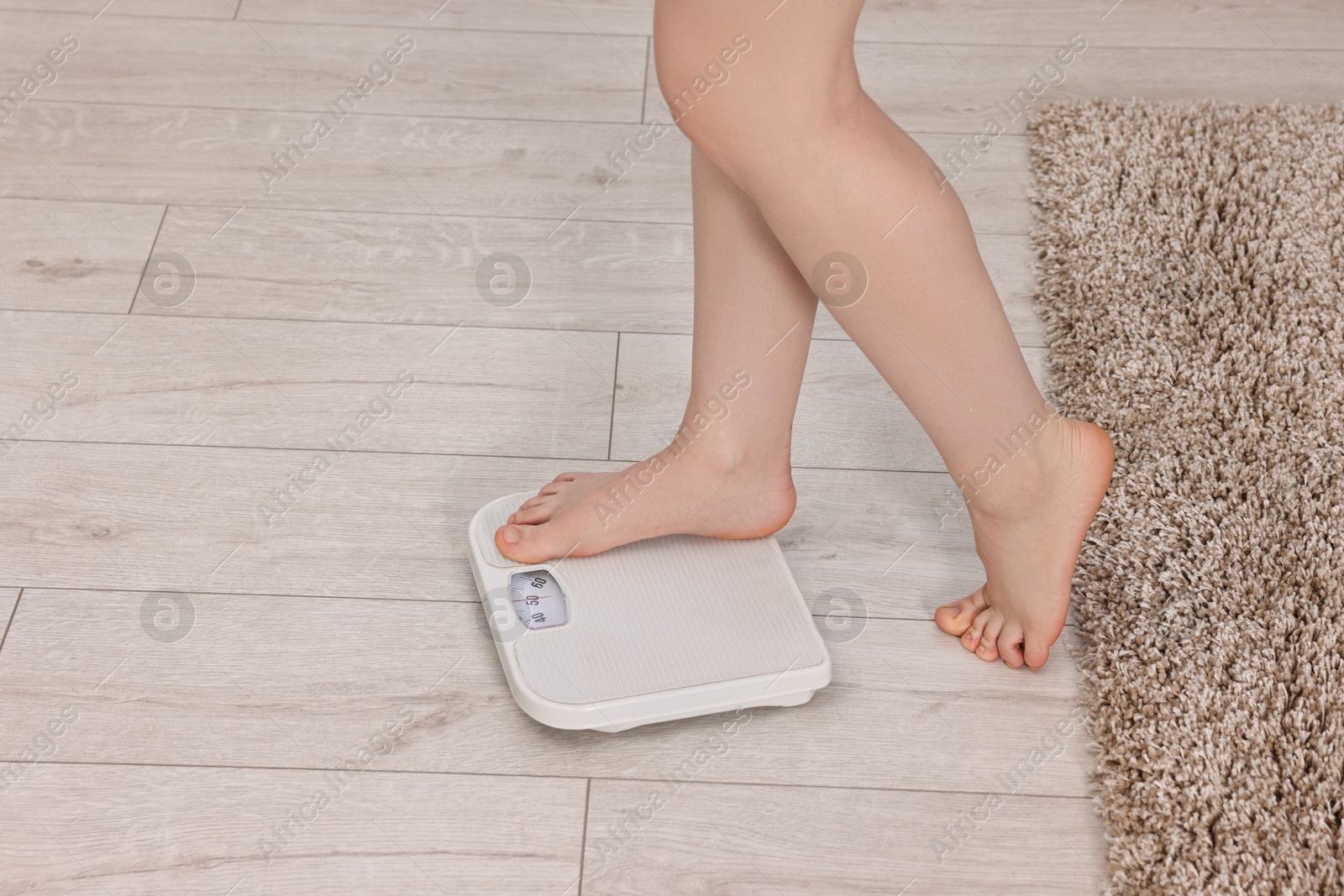 Photo of Woman stepping on floor scale at home, closeup. Space for text