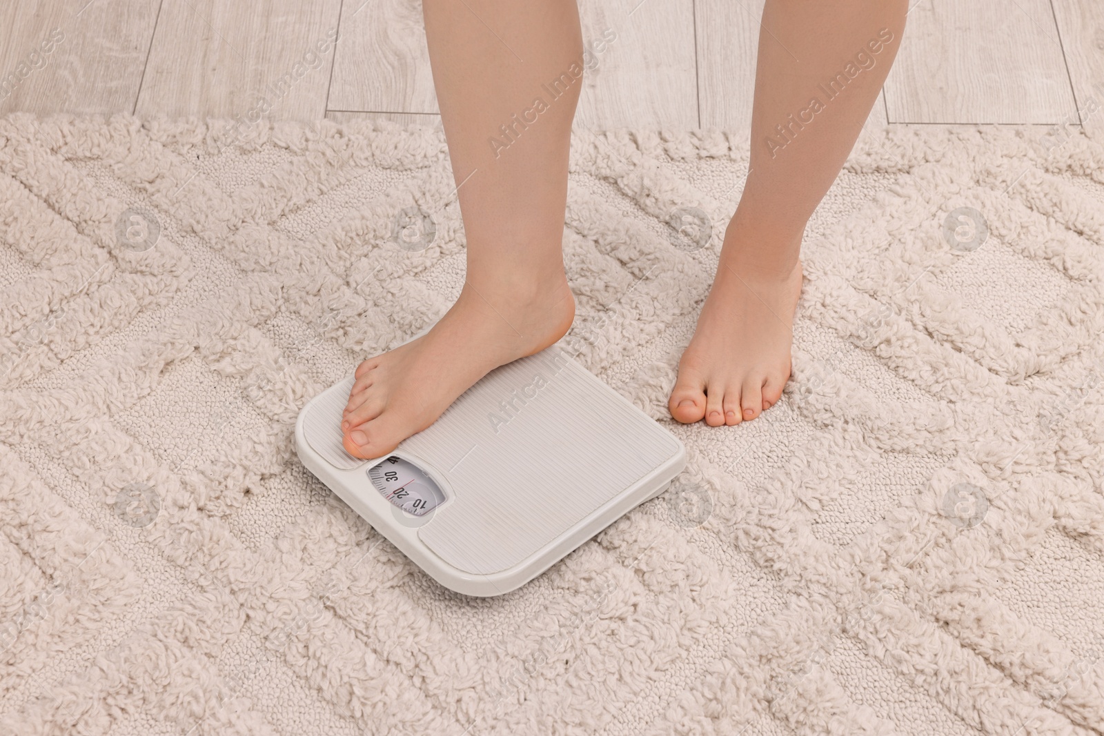 Photo of Woman stepping on floor scale at home, closeup