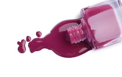 Photo of Overturned bottle of violet nail polish isolated on white, top view