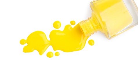 Overturned bottle of yellow nail polish isolated on white, top view