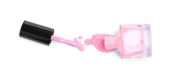 Photo of Overturned bottle of pink nail polish and brush isolated on white, top view
