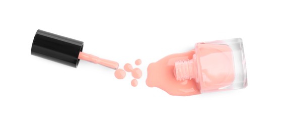 Photo of Overturned bottle of coral nail polish and brush isolated on white, top view