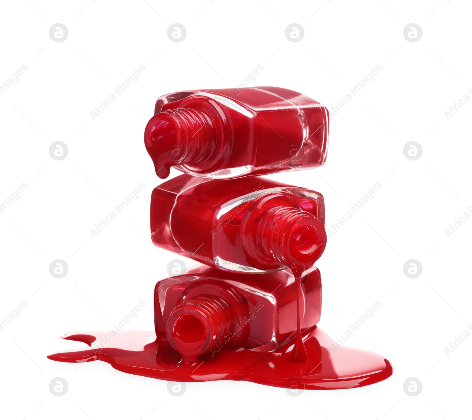 Photo of Red nail polishes dripping from bottles on white background