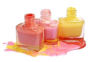 Puddle of different bright nail polishes and bottles isolated on white