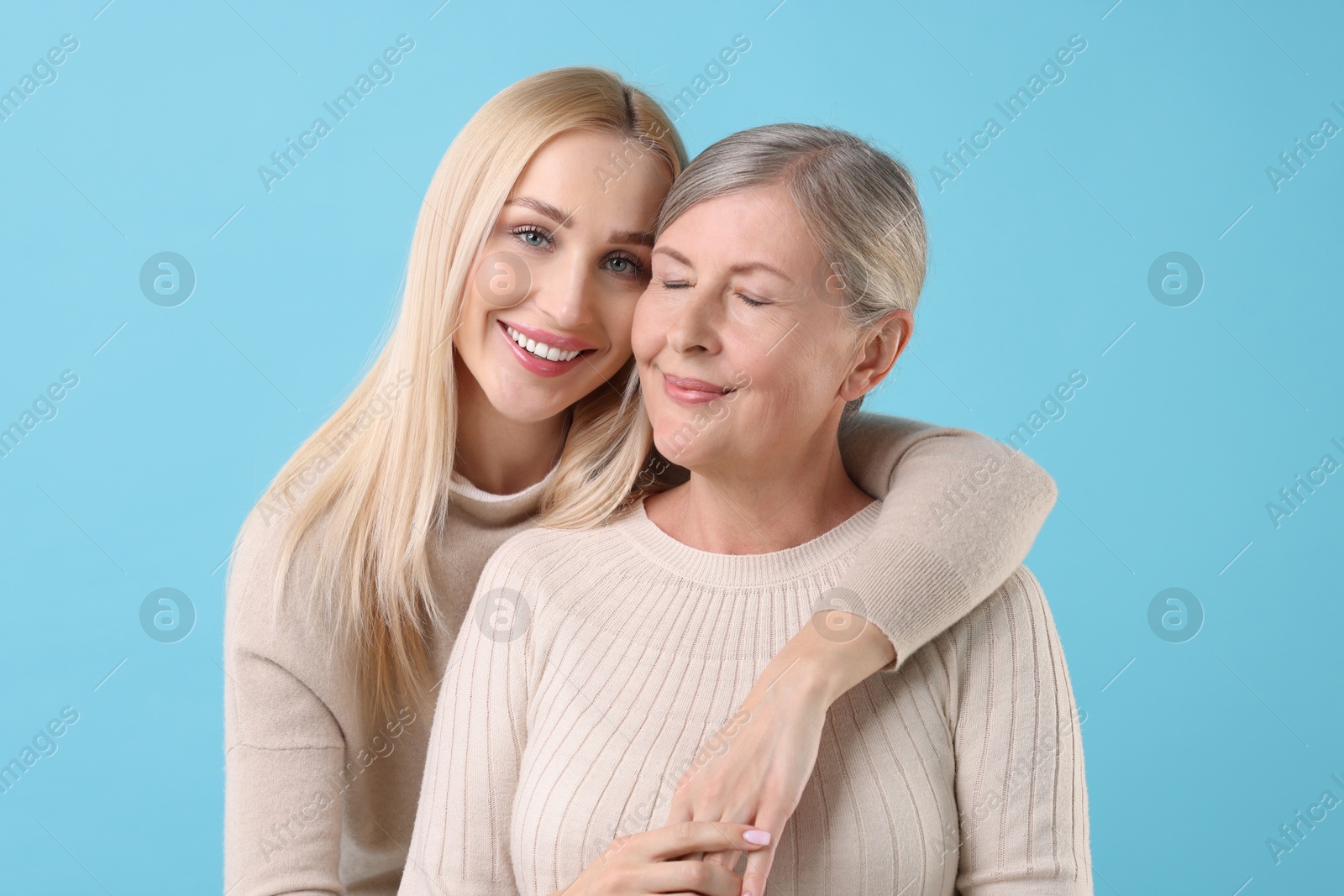 Photo of Family portrait of young woman and her mother on light blue background