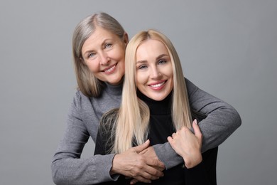 Photo of Family portrait of young woman and her mother on grey background