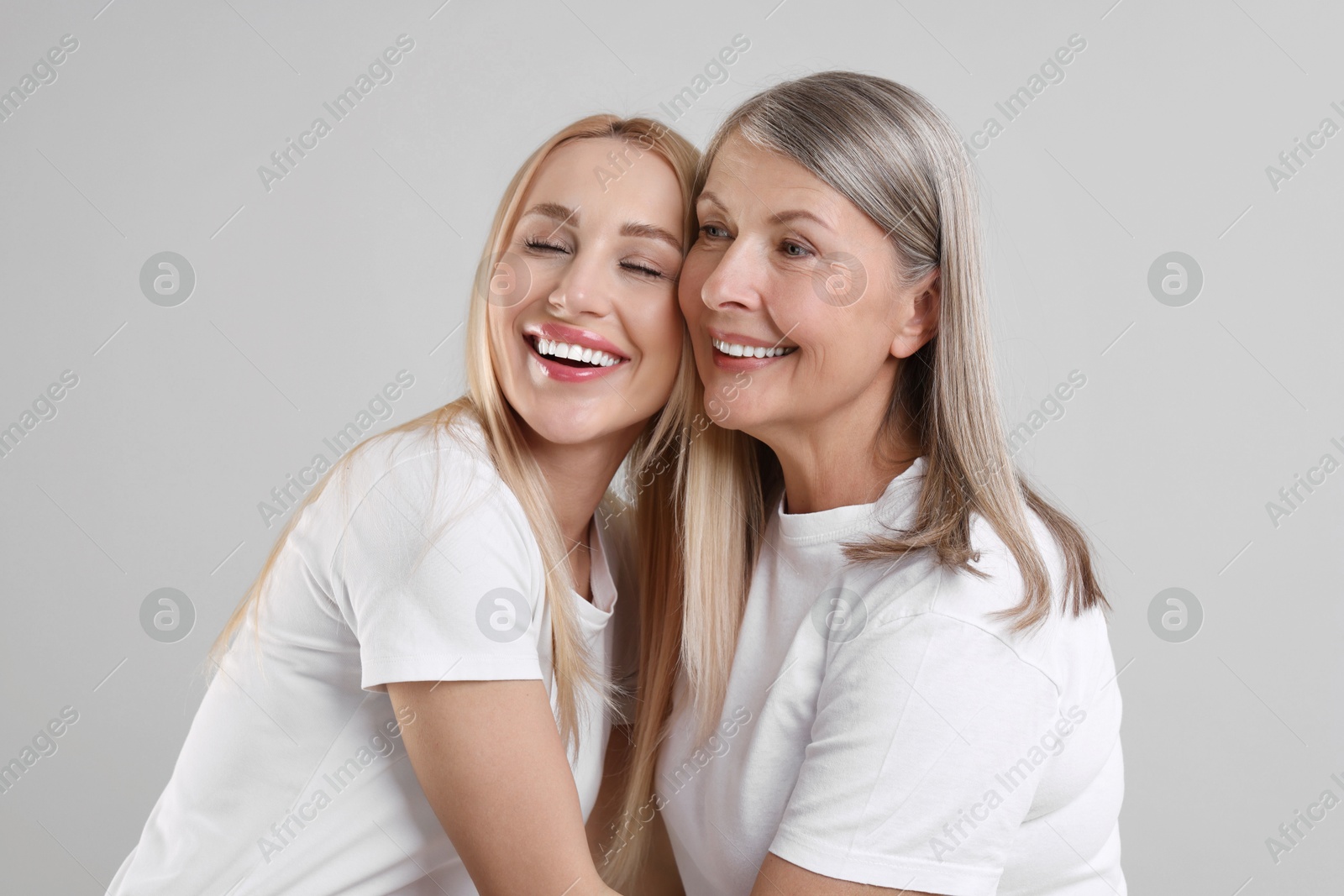 Photo of Family portrait of young woman and her mother on light grey background