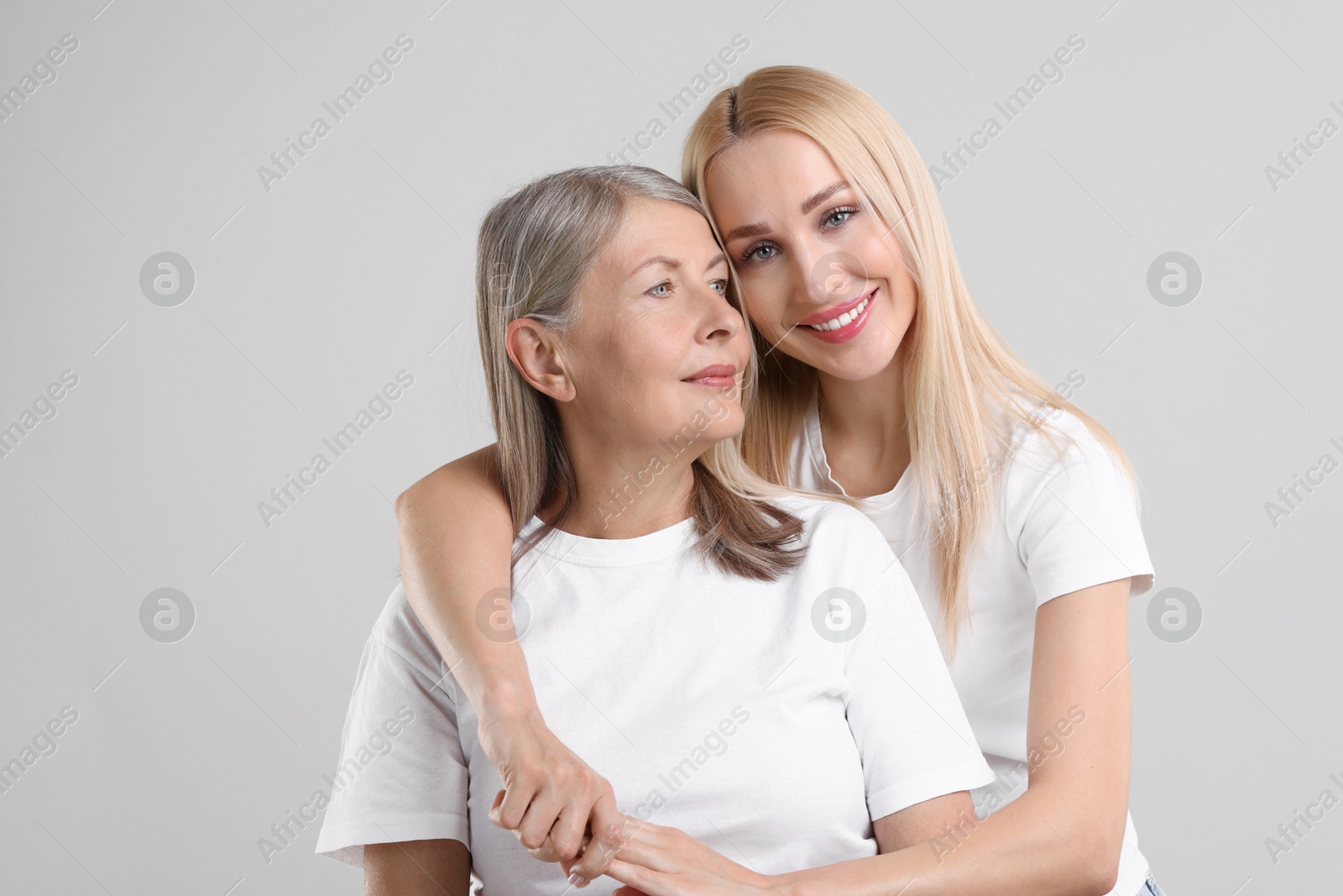 Photo of Family portrait of young woman and her mother on light grey background