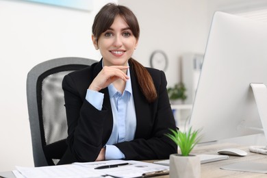 Portrait of smiling secretary at table in office